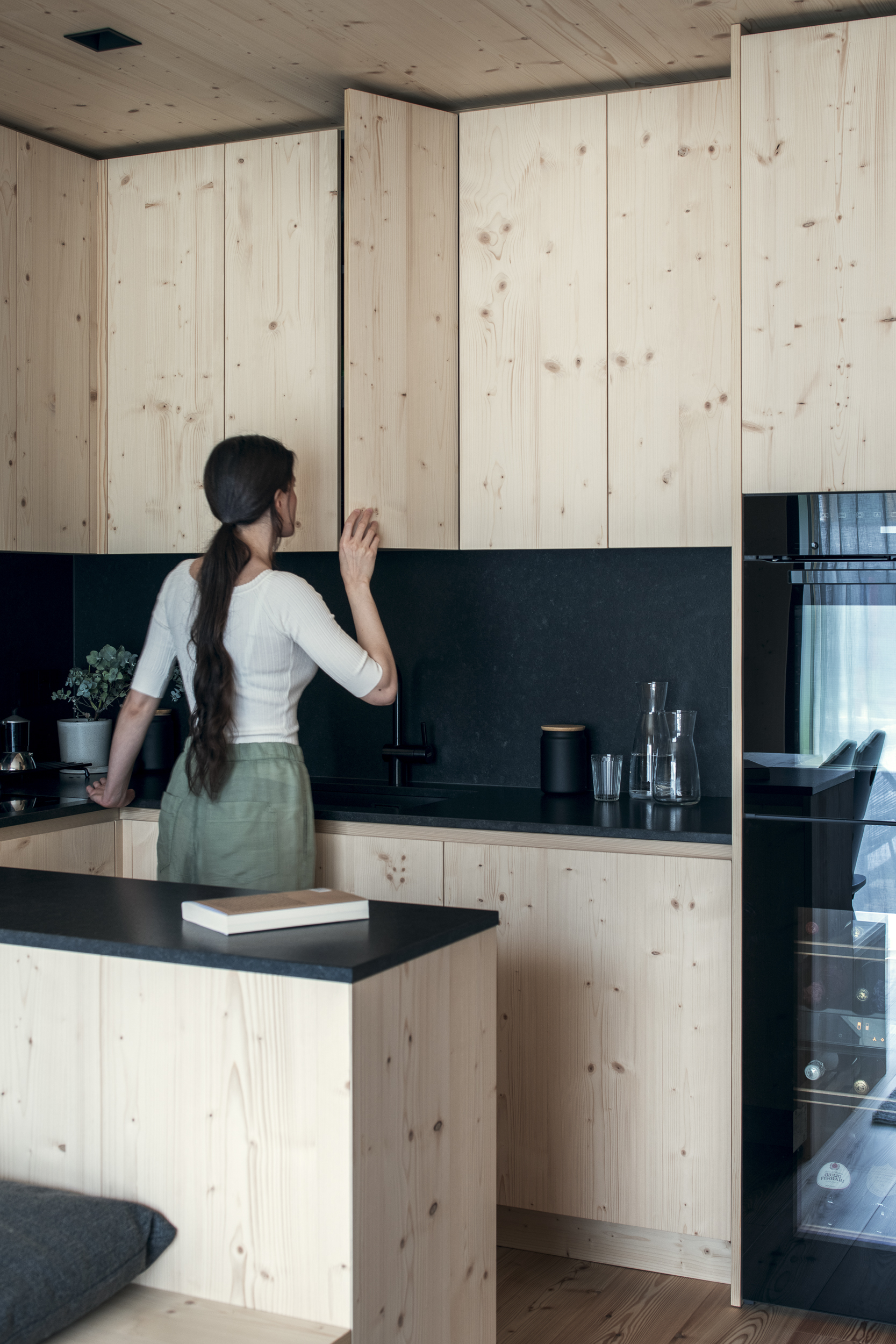 Cucina su misura Corazzolla in stile alpino, realizzata in legno di abete bianco e gres nero con soffitto rivestito in abete bianco a Madonna di Campiglio