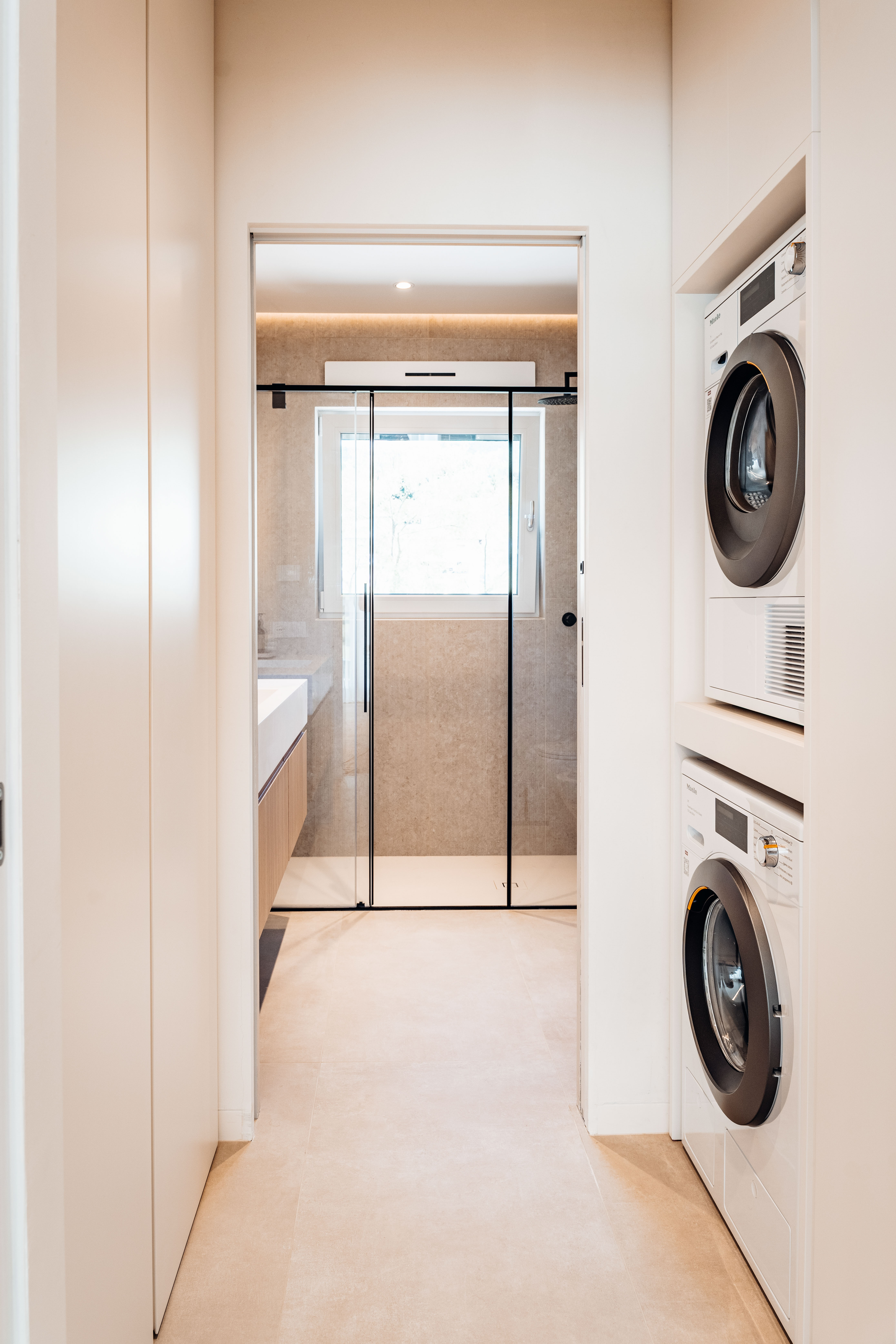 Lavanderia su misura Corazzolla in legno laccato crema integrata nel passaggio verso il bagno