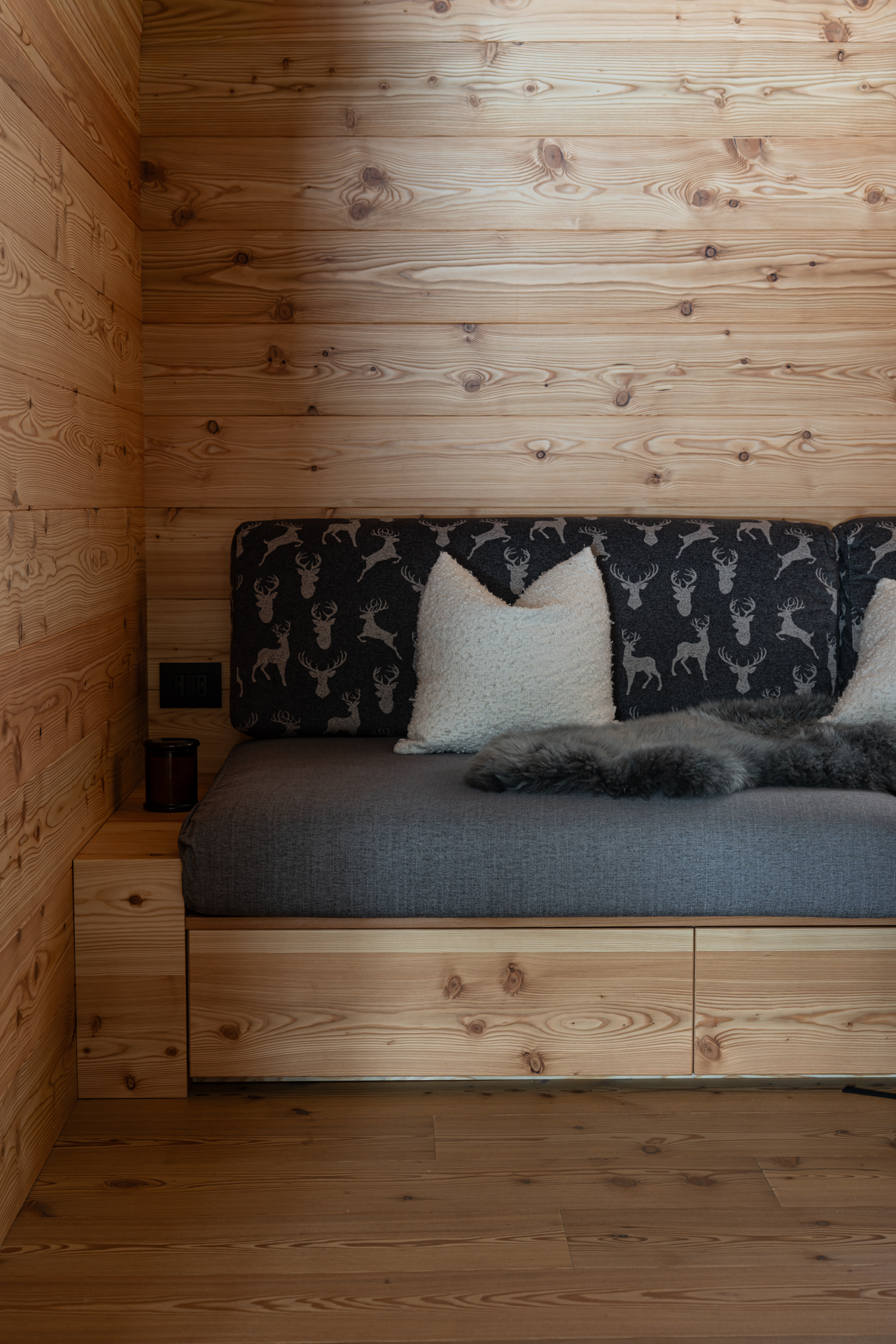 living chalet di montagna con rivestimento a doghe di larice e divano in legno realizzato su misura da Corazzolla