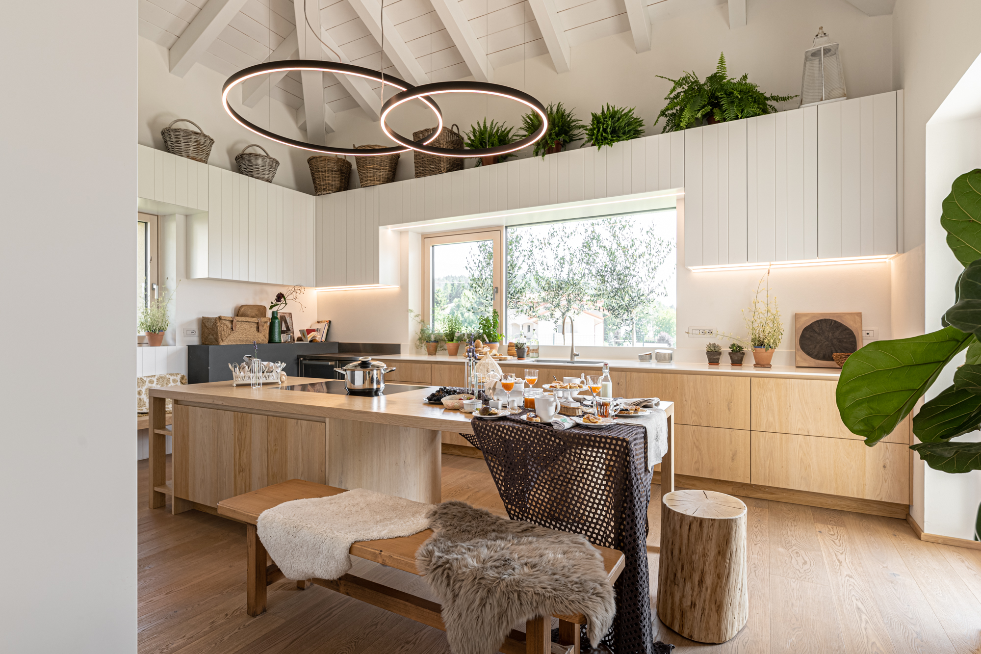 Cucina su misura con isola in rovere naturale, piano in Krion bianco e armadiature laccate con fresature verticali