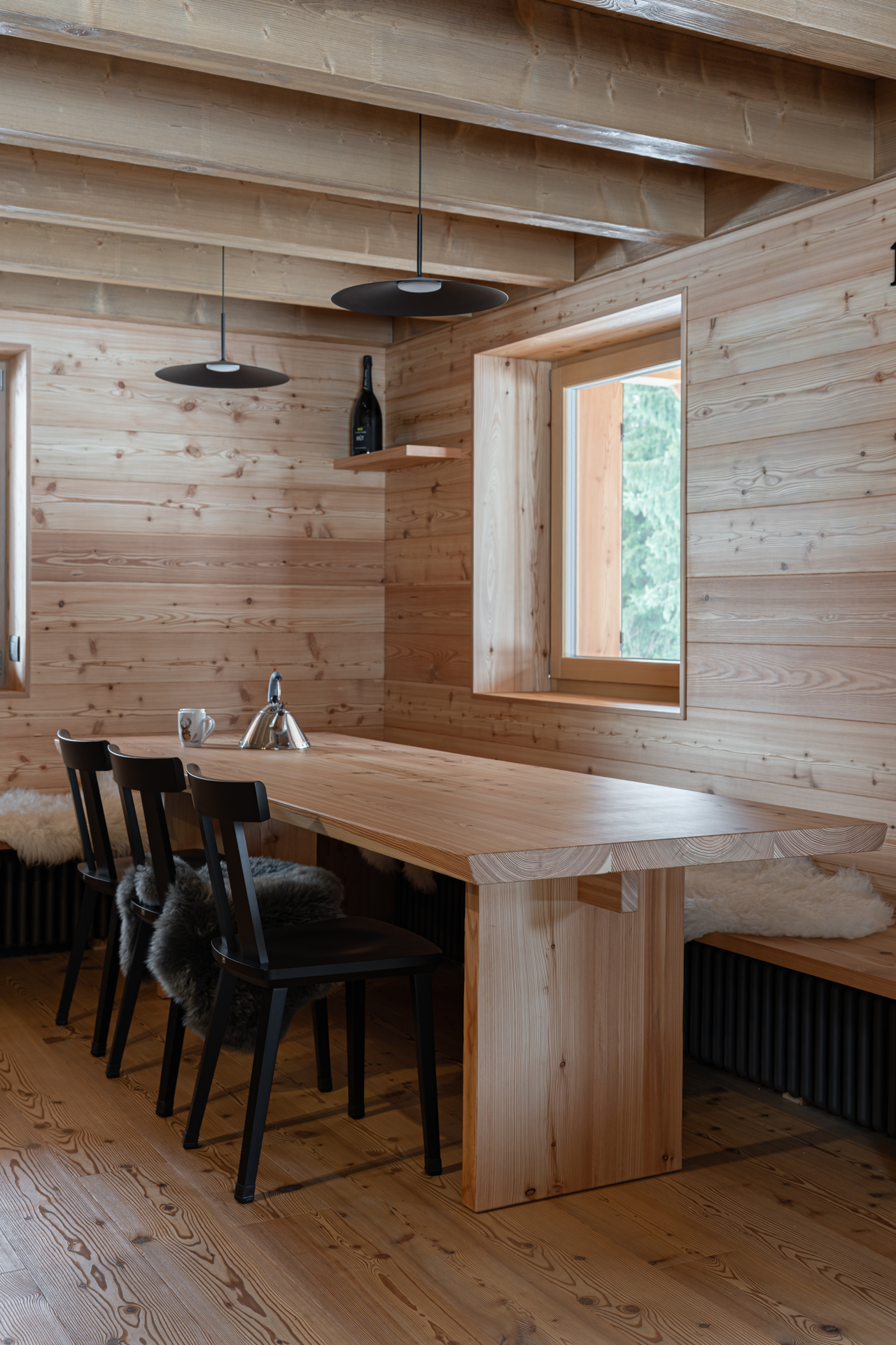sala pranzo con rivestimento a doghe di larice e tavolo con panca realizzato su misura da Corazzolla