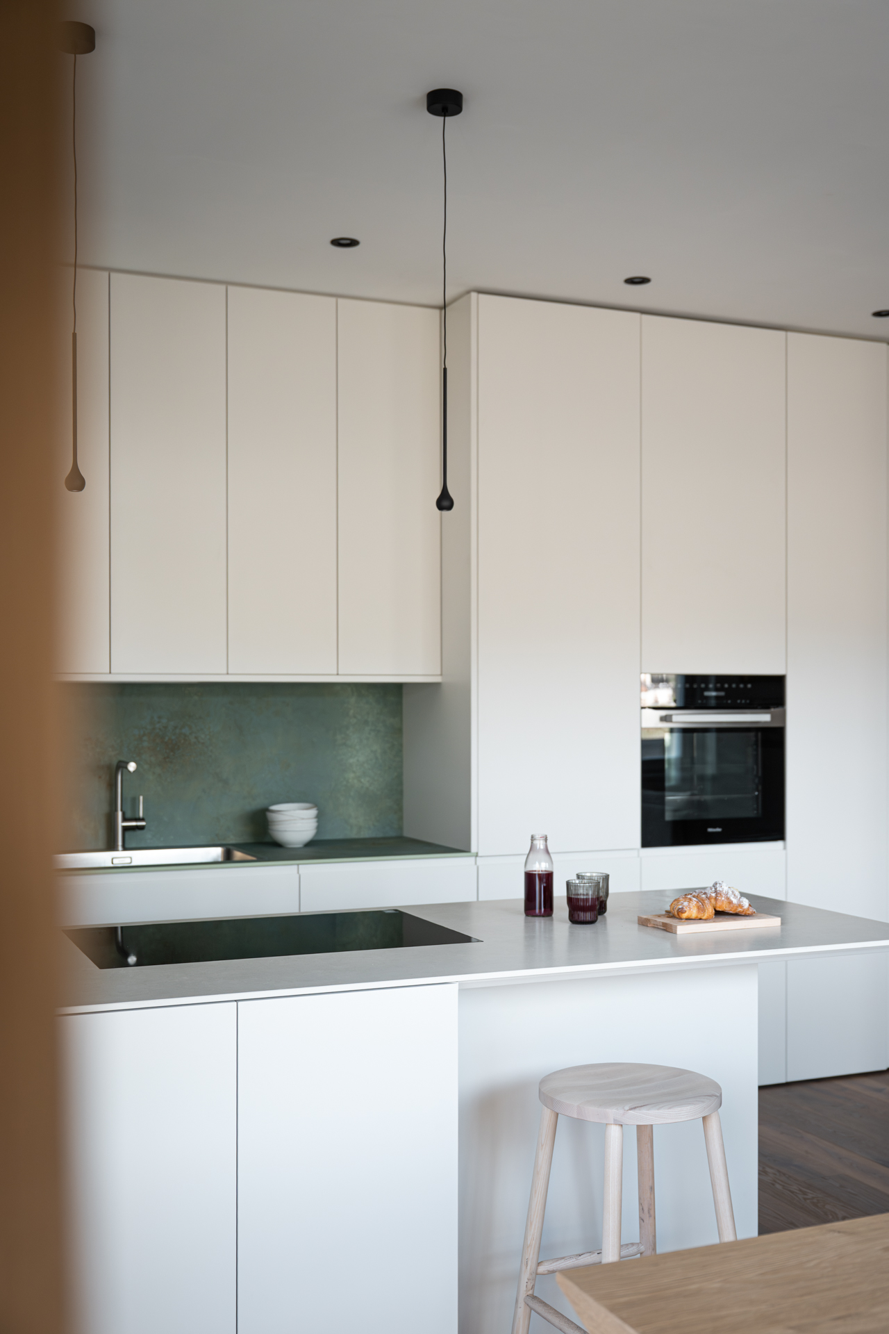 cucina su misura minimale in legno laccato crema e piano verde, realizzata da Corazzolla