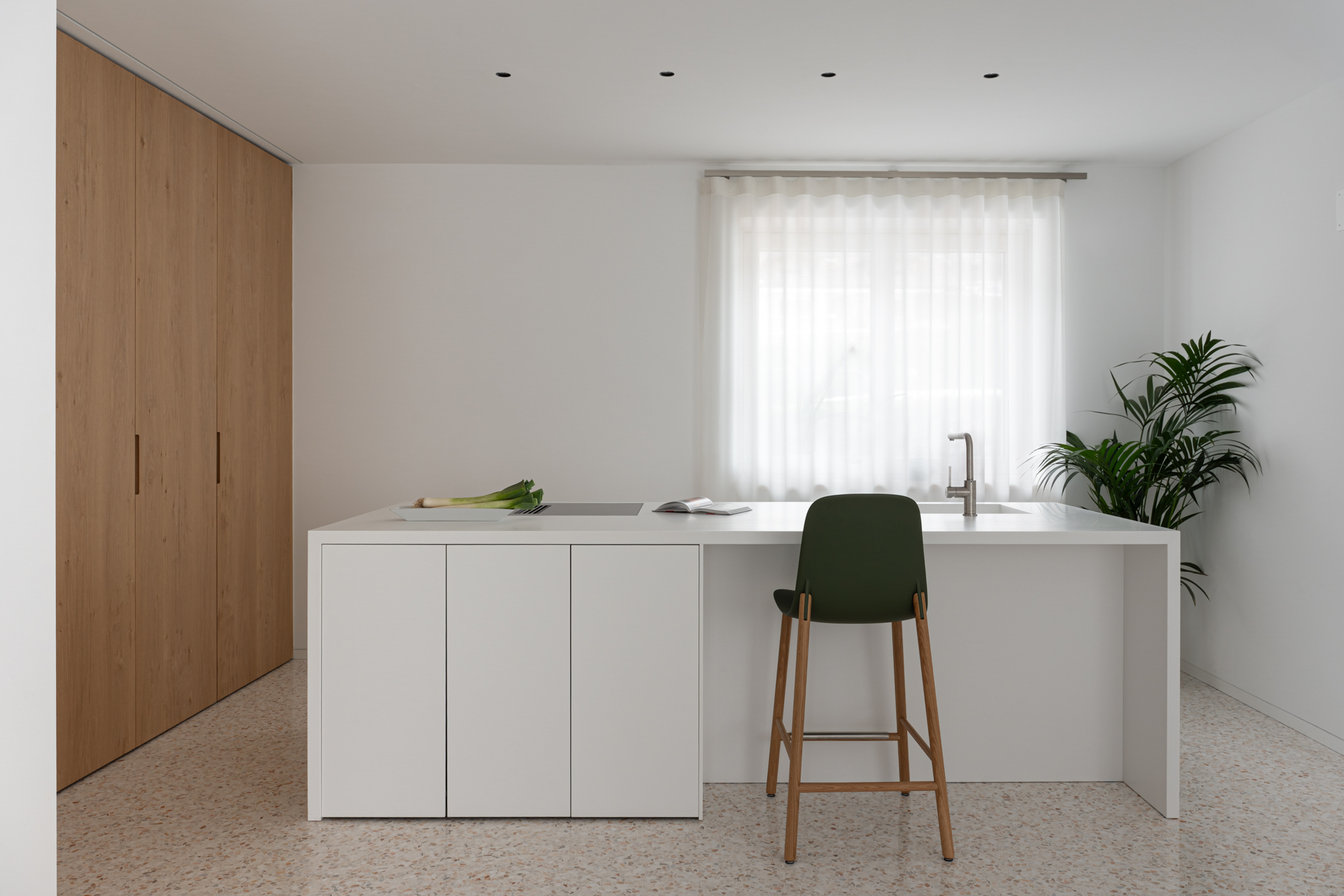 Cucina su misura Corazzolla in stile minimal con isola in Krion e piano snack. Armadiature a tutt’altezza con elettrodomestici integrati, ante a pacchetto in legno di rovere.