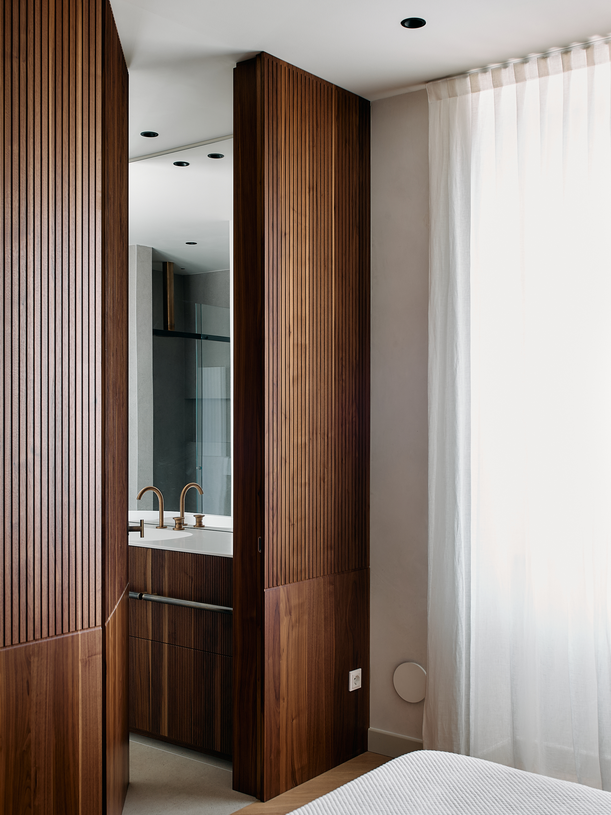 Parete divisoria contenitiva in noce canaletto con lavorazione artigianale a fresature verticali, realizzazione Corazzolla